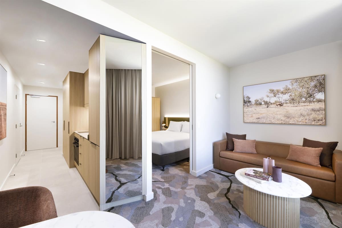 A hotel room with a bed, a sofa, a coffee table, and a painting on the wall.