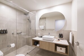 A modern bathroom with a glass-enclosed shower, a white sink, and a mirror above the vanity. - Adina Chermside Brisbane (Brisbane)