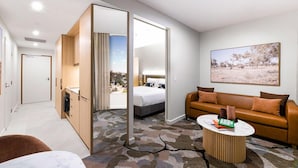A modern hotel room with a large bed, a sofa, a coffee table, and a view of a landscape through the window. - Adina Chermside Brisbane (Brisbane)