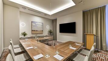 A conference room with a long table, chairs, a TV, and a podium.