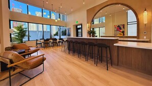 A spacious bar area with high ceilings, large windows offering views of the city, and a modern interior design with wooden flooring and bar stools. - Luxury 1BR Downtown Miami  / Rooftop Pool / Free Parking  / Gym / Work Space (Miami)