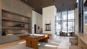 A modern living room with a pool table, a bar area, and large windows offering a city view. - Luxury 1BR Downtown Miami  / Rooftop Pool / Free Parking  / Gym / Work Space (Miami)