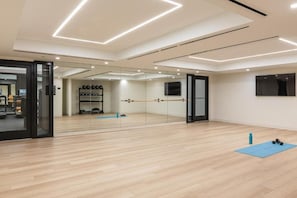 A modern gym with wooden floors, a mirrored wall, and exercise equipment. - Luxury 1BR Downtown Miami  / Rooftop Pool / Free Parking  / Gym / Work Space (Miami)