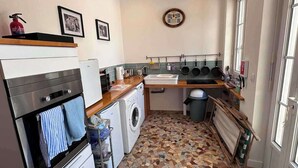 A compact kitchen with a washing machine, a stove, and a sink. - Pet Friendly & Accessible 3-Bed Gite, Sleeps 6 (Sourdeval)