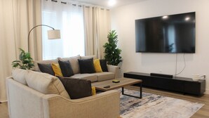 Un salon moderne avec un canapé, une table basse et un téléviseur à écran plat fixé au mur.
