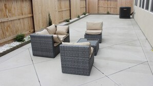 Une terrasse dotée de meubles en osier et d’une clôture en bois.