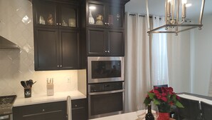 Une cuisine moderne avec des meubles de couleur sombre, des appareils électroménagers en acier inoxydable et un plan de travail en bois.
