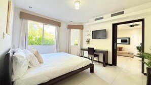 Ein Schlafzimmer mit einem Bett, einem Schreibtisch, einem Sessel, einem Fernseher und einem Sofa.