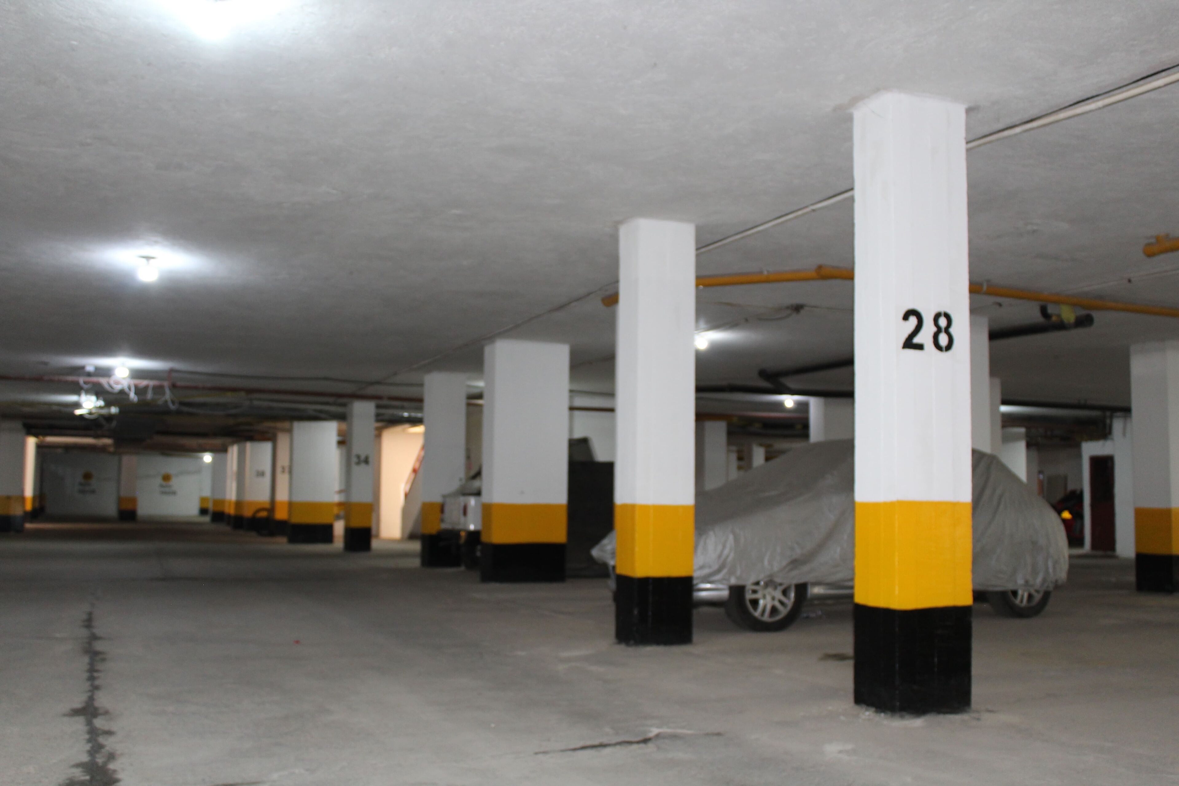 Een parkeergarage met witte pilaren, voorzien van nummers, waaronder 28.