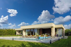 Una casa moderna con piscina, area relax esterna e prato curato.