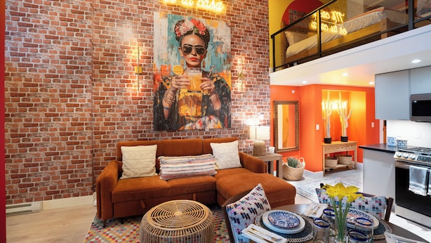 Een moderne woonkamer met een bakstenen muur, een bank, een salontafel en een keuken met een fornuis.