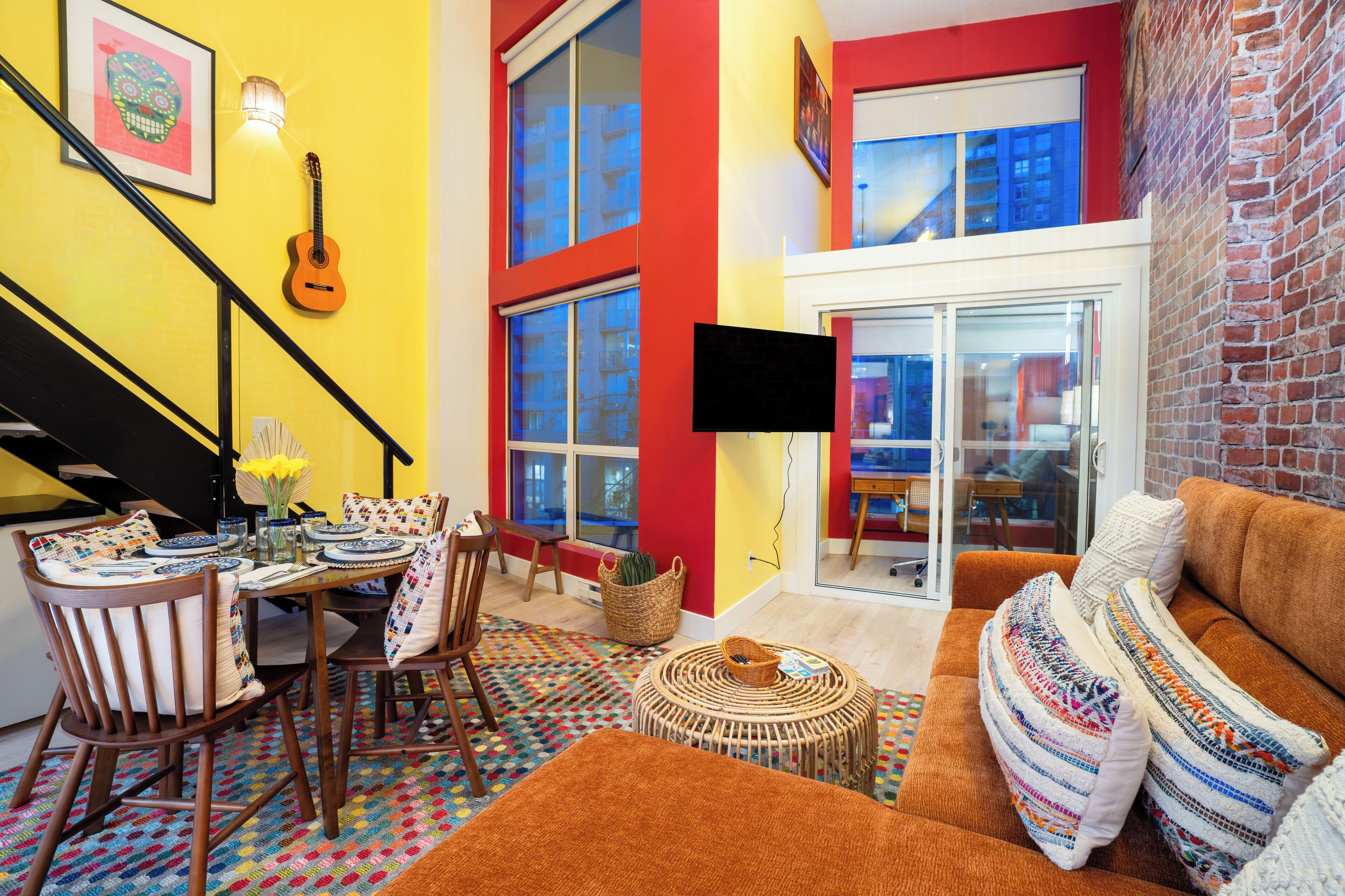 Een kleurrijke woonkamer met een bank, een salontafel en een eethoek met stoelen en een tafel.