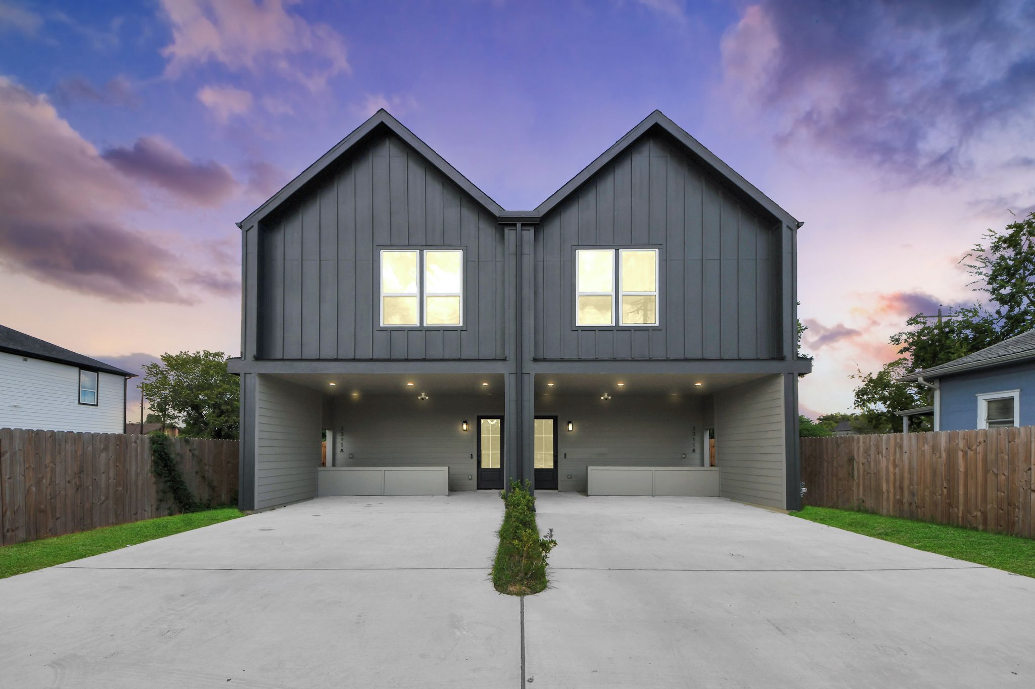 A two-story house with a symmetrical design, featuring a central entrance and a driveway leading to the front.