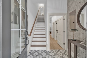 A modern staircase leading to a hallway with patterned flooring and a mirror on the wall. - Mega Market 6BR Home in Houston Groups Sleeps 12+ (Houston)