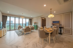 Un comedor con piso de mármol, una mesa dispuesta para seis personas y vistas a la ciudad a través de amplias ventanas.
