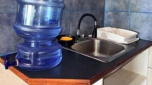 A kitchen with a water dispenser, a sink, and a dish rack. - Lily's House, entire cabin in San Juan La Laguna (Solola)