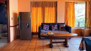 A living room with a sofa, a table, a refrigerator, and curtains. - Lily's House, entire cabin in San Juan La Laguna (Solola)