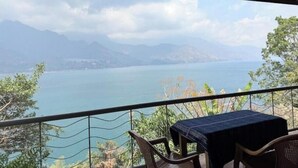 A balcony with a table and chairs overlooking a calm lake and distant mountains. - Lily's House, entire cabin in San Juan La Laguna (Solola)