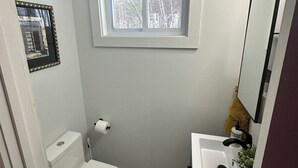 A bathroom with a toilet, sink, and window.