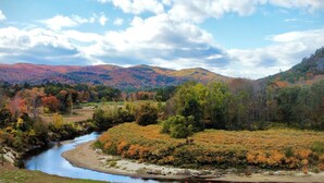 A river flowing through a valley with autumn foliage and hills in the background.