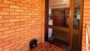 Un mur de briques avec une porte en verre portant l’inscription « Salle commune ».