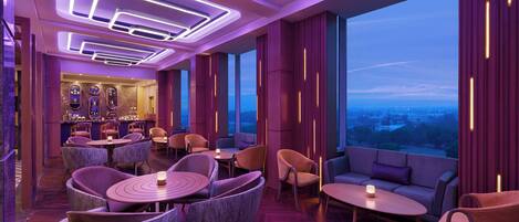 A modern interior with seating arrangements, a bar area, and large windows offering a view.