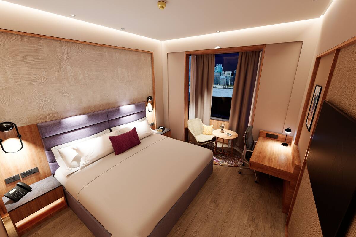 Une chambre d’hôtel avec un grand lit, un bureau, une chaise et une vue sur le paysage urbain par la fenêtre.