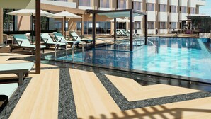 A hotel pool area with sun loungers, umbrellas, and a clear pool. - Vivanta Gurugram, Sector 95A (Gurugram)