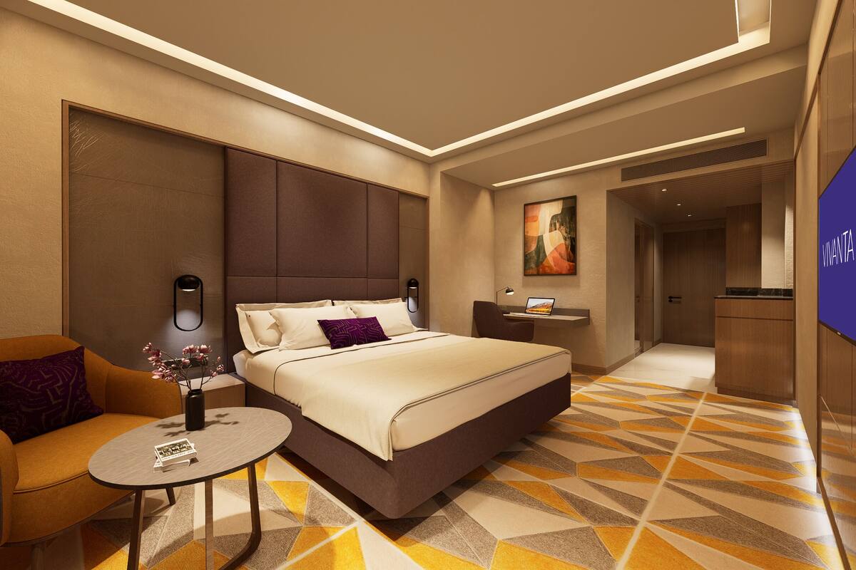 Une chambre d’hôtel moderne avec un grand lit, un canapé, une petite table et un téléviseur.