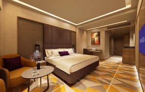 A modern hotel room with a large bed, a sofa, a small table, and a TV.