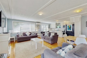 A modern living room with two sofas, a coffee table, and a kitchen area with cabinets and appliances. - Cozy coastal cottage with modern kitchen, dog-friendly spaces, and beach access (Ocean Shores)