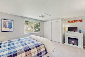 A bedroom with a bed, a fireplace, a television, and a window. - Cozy coastal cottage with modern kitchen, dog-friendly spaces, and beach access (Ocean Shores)