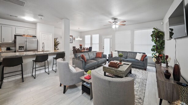 A modern living room with a gray sofa, a coffee table, and a dining area with bar stools. - Cozy, Comfy, Warm Relaxing Home (Conroe)