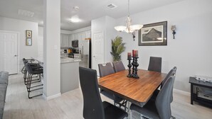 A modern kitchen with white cabinets, a wooden dining table, and black chairs. - Cozy, Comfy, Warm Relaxing Home (Conroe)