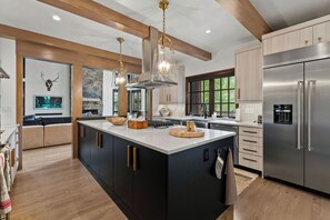A modern kitchen with a large island, stainless steel appliances, and a stone fireplace.