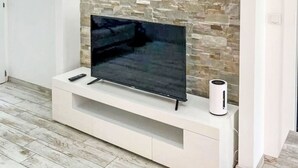 En platt-TV placerad på en vit TV-bänk mot en vägg av sten.
