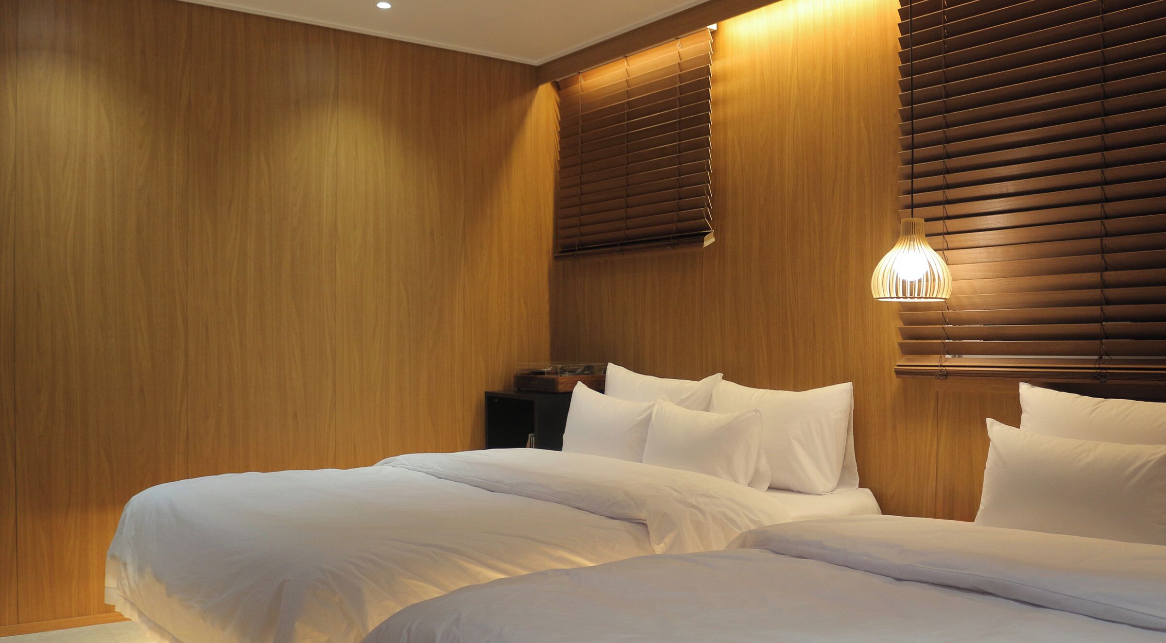 A hotel room with a large bed, wooden paneling on the walls, and a nightstand with a lamp.