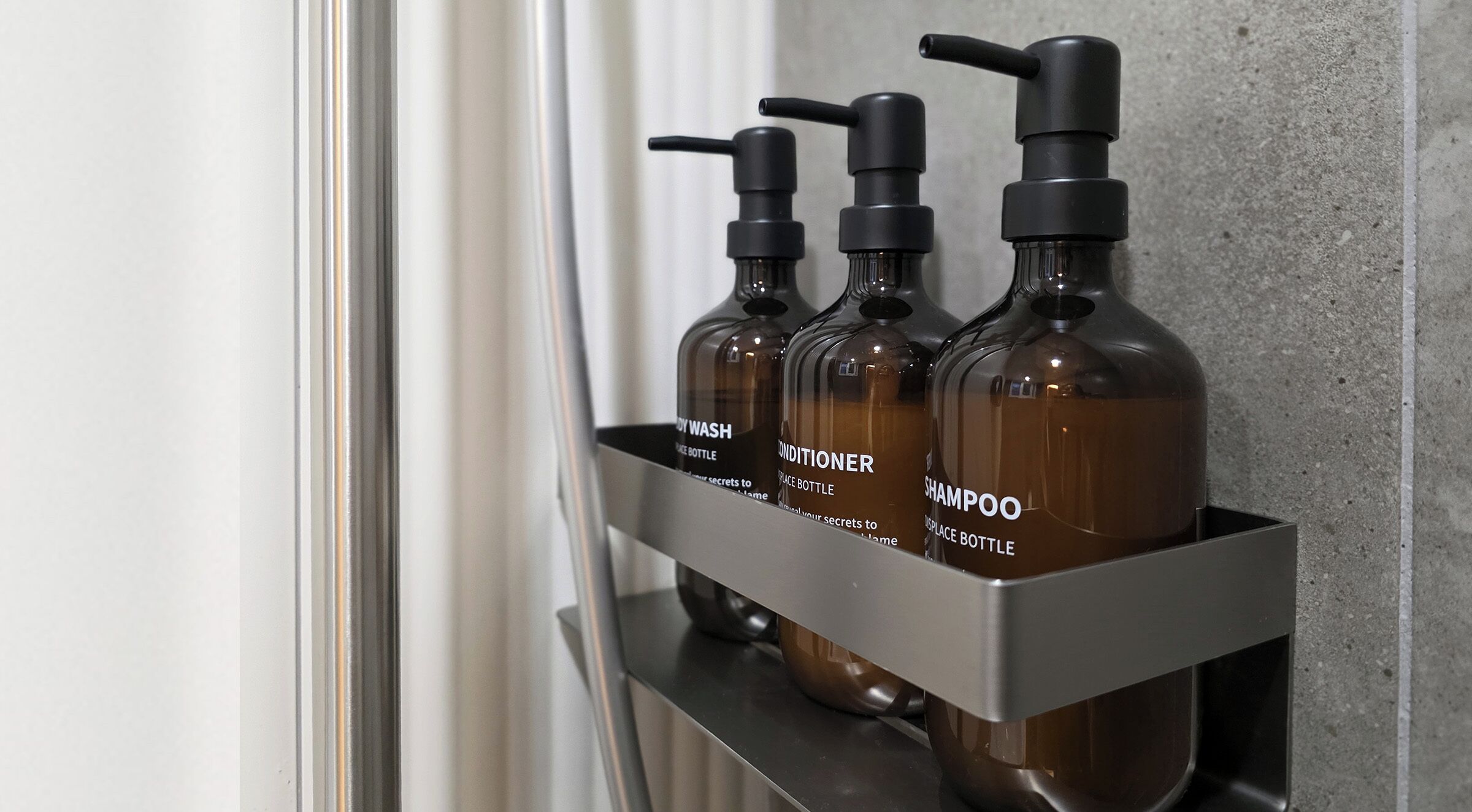 A metal shelf with three bottles of hair care products.