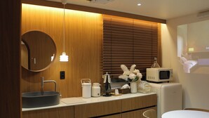 Un baño moderno con un espejo redondo, tocador de madera y un microondas.