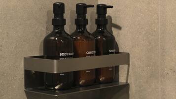A shelf with three bottles labeled "BODY WASH," "CONDITIONER," and "SHAMPOO."