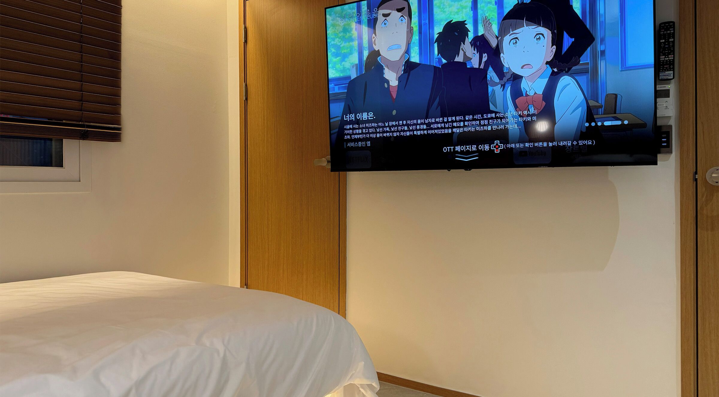 A hotel room with a bed, a television mounted on the wall, and a wooden panel.