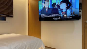 A hotel room with a bed, a television mounted on the wall, and a wooden panel.
