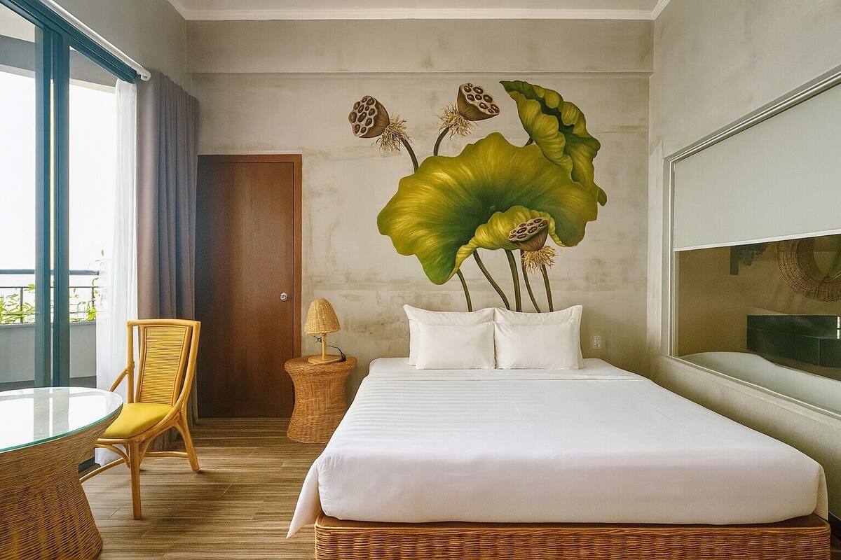 Une chambre d’hôtel avec un lit, une chaise, une table et une grande fenêtre.