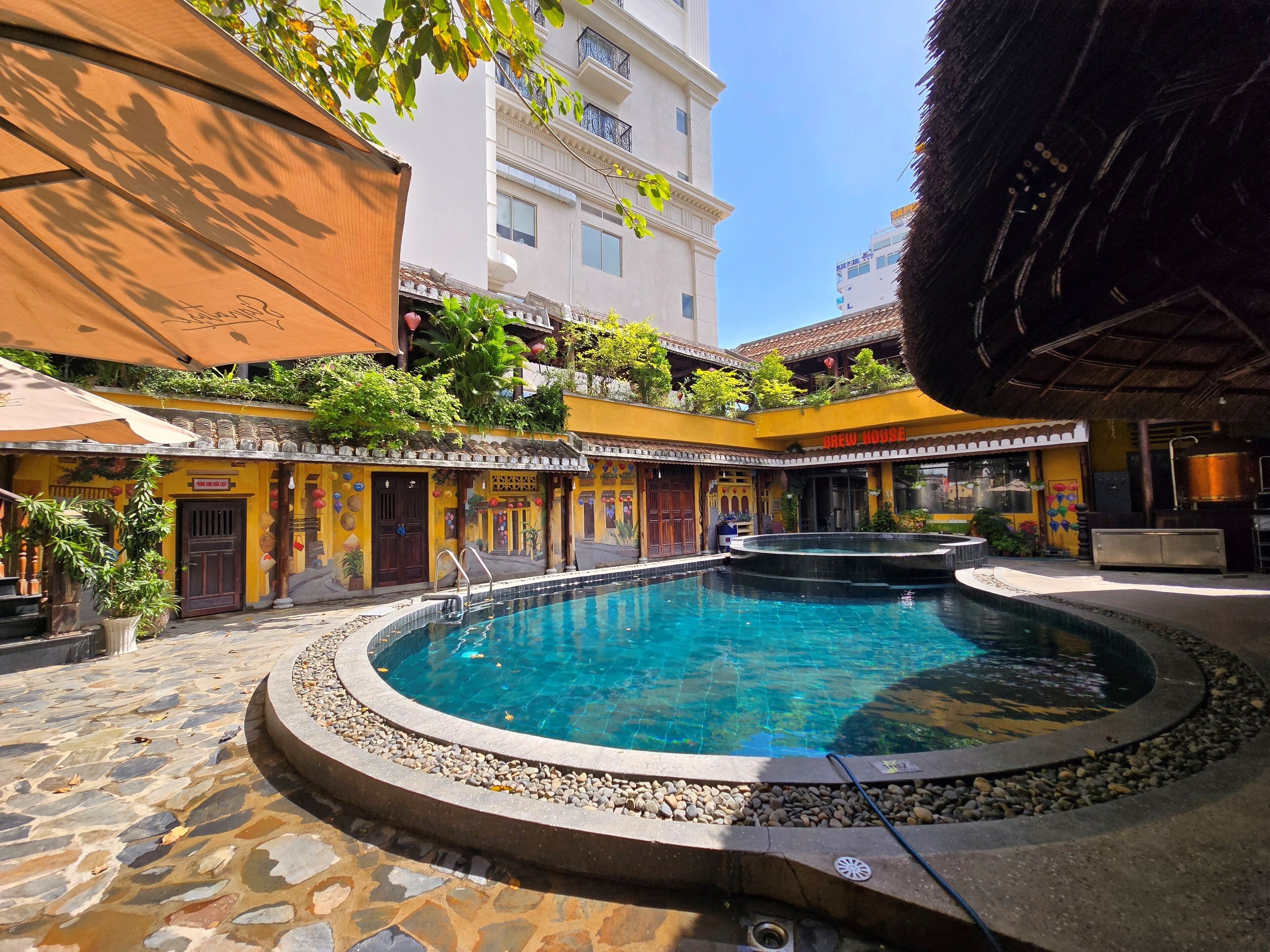 Une cour avec une piscine, une enseigne indiquant « Brasserie », et un bâtiment doté de balcons.