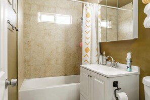 Une salle de bain avec une baignoire, un lavabo équipé de produits de toilette et un miroir.