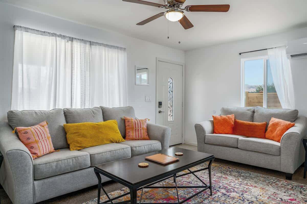 A living room with two grey sofas, a coffee table, and a ceiling fan.