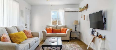 Uma sala de estar com sofá, mesa de centro e televisão.