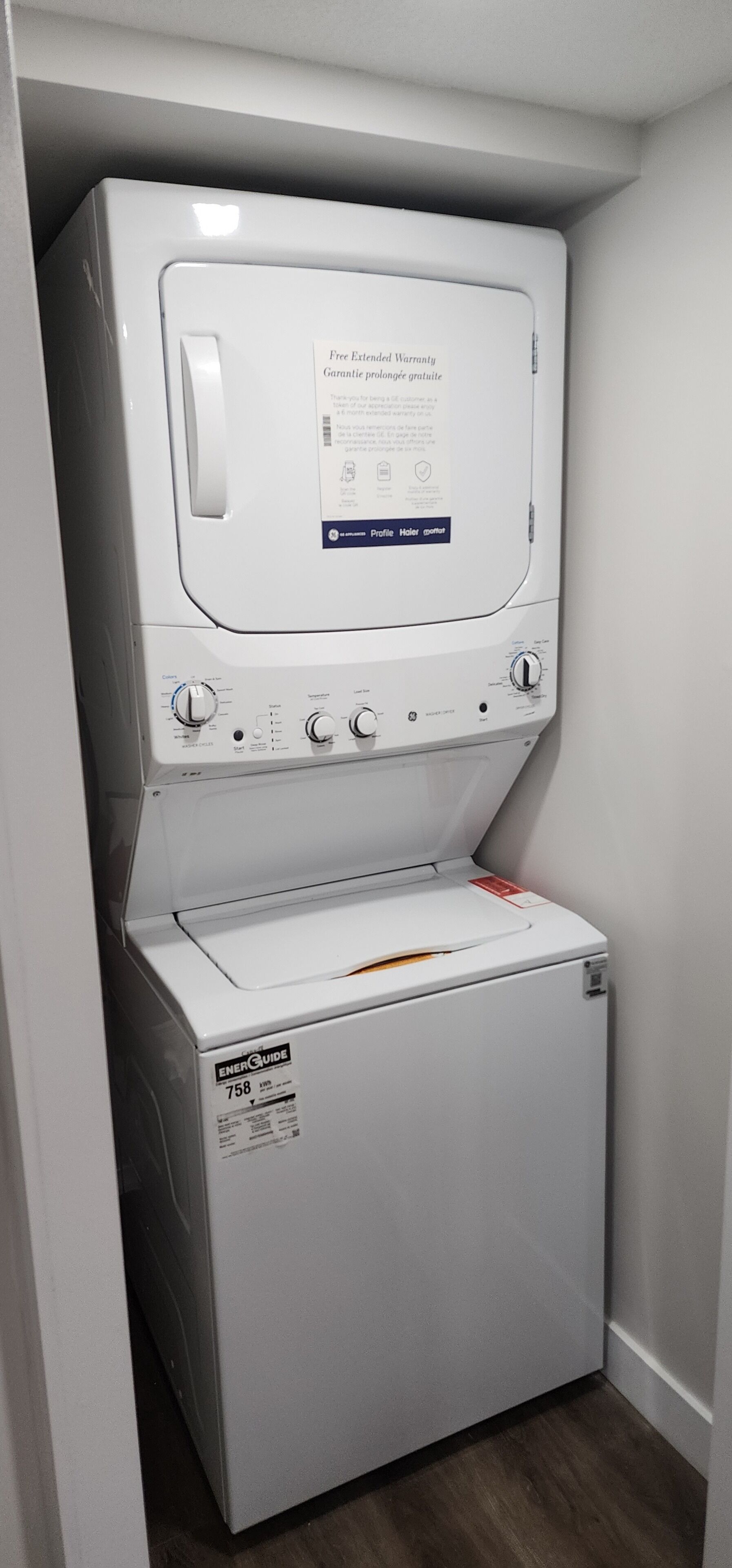 A front-loading washer and dryer unit with a control panel and a label indicating a free extended warranty.