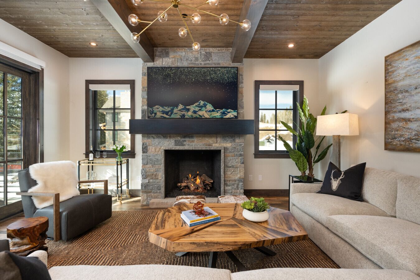 Una sala de estar moderna con chimenea de piedra, un ventanal grande y una zona de estar acogedora.