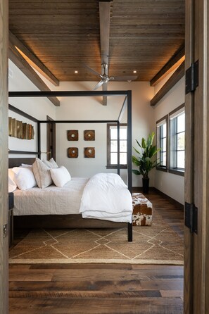 Um quarto espaçoso com cama de dossel, piso de madeira e uma grande janela que proporciona iluminação natural.